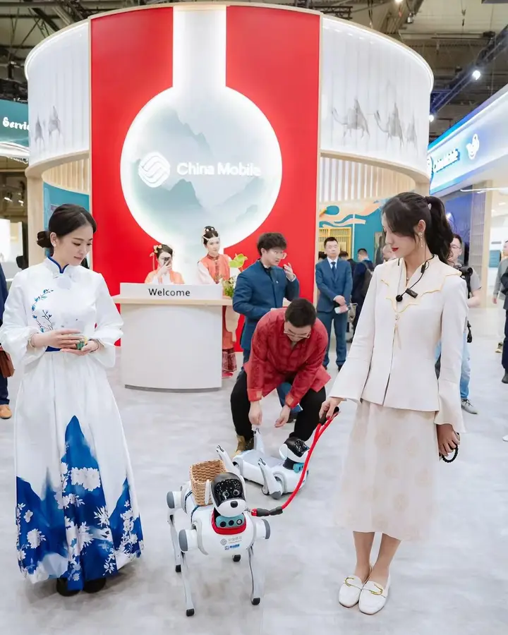 Azafatas de China Mobile guiando robots de compañía en su stand del MWC